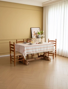 Close-up of cream rectangular tablecloth with orange embroidery and white tassel fringe