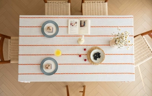 Detail of Nordic cotton linen tablecloth with orange diamond pattern and white tassels