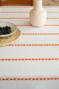 Detailed close-up of cotton linen tablecloth featuring orange embroidery and tassels