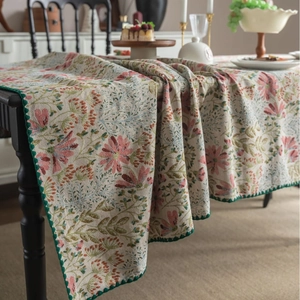 French vintage floral jacquard tablecloth with dark green scalloped edges on dining table