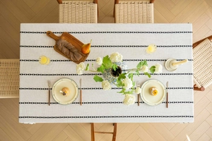 Bird's eye view of rectangular linen tablecloth with black geometric embroidery and tassels