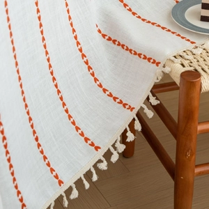 White linen table runner with orange heart embroidery and beige tassels for dining decor