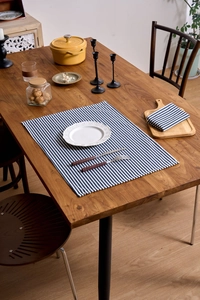 Detailed close-up of blue striped linen napkins and placemats on a rustic wooden table