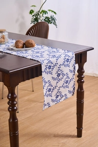 Detail of French country style table runner with blue floral print on white cotton linen