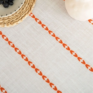 White linen table runner with orange embroidery and fringe detail for home decor