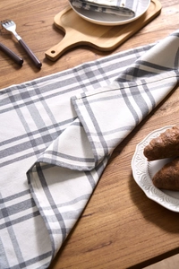 Detail einer grau-weiß karierten Stoffserviette aus Leinen auf einem Holztisch
