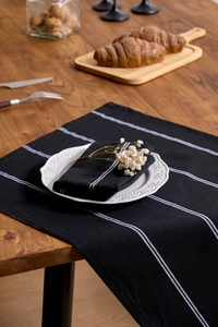 Detail of black and white striped napkins and placemat set on a rustic wooden table