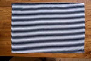 Close-up of blue and white striped placemat with reinforced stitching on a wooden table