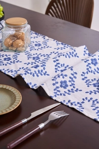 Detail of floral table runner on dark wood, showing high-quality linen texture and pattern