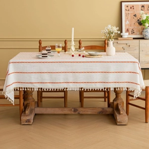 Rectangular cream tablecloth with orange geometric embroidery and white tassels