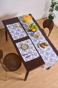Close-up of blue floral table runner and placemats on dark wooden dining table