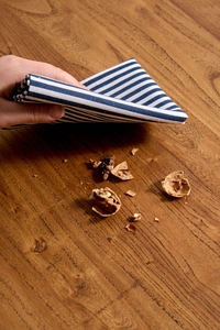 Detail of blue striped cotton linen napkin cleaning crumbs on a wooden table surface