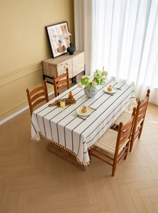 Close-up of beige rectangular tablecloth featuring black stripes and elegant tassel fringe
