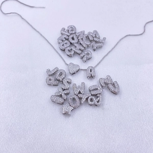 Gros plan sur pendentifs lettres bulles dorés 18K ornés de zircons brillants