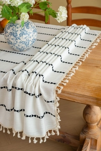 Close-up of beige cotton linen table runner with black wave embroidery and tassels