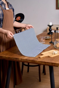 Close-up of blue and white striped cotton-linen placemat on a warm wooden dining table