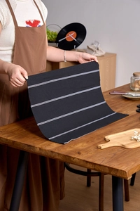 Detail of Nordic black and white striped cotton napkin held by hands on a wooden table