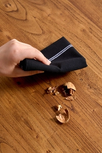 Close-up of black cotton napkin cleaning walnut shells on a rustic wooden table surface