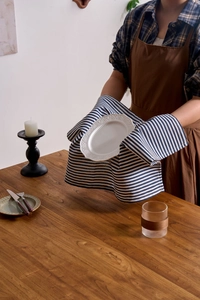 Close-up of blue striped linen napkin held with a white embossed ceramic plate on wood table