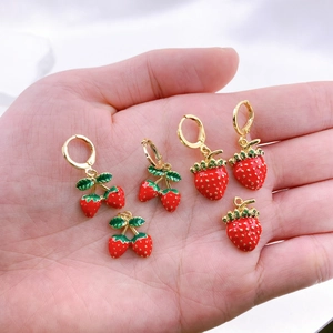 Dettaglio di ciondoli per orecchini fragola in smalto rosso con foglie dorate