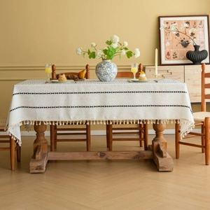 Rectangular beige linen tablecloth with black geometric embroidery and tassel edges