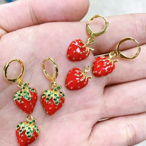 Vista dettagliata degli orecchini a fragola rossa con foglie d'oro e zirconi verdi