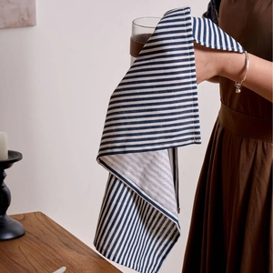 Japanese style blue striped cotton linen napkin hanging over a wooden dining table