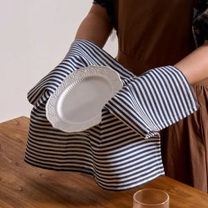 Blue striped cotton linen napkin wrapped around an embossed ceramic plate on a wooden table