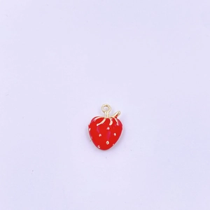 Dettaglio di un piccolo ciondolo a fragola rossa smaltata con punti dorati e anello