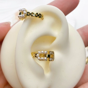 Detail of gold belt buckle ear cuff with white pearls and rhinestones on fake ear