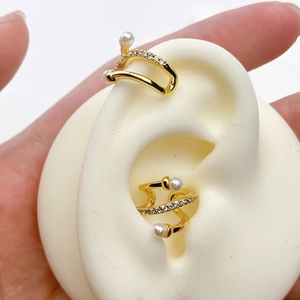 Detail der goldenen Ohrmanschetten mit Zirkonia und Perlen im minimalistischen Doppellinien-Design