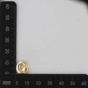 Macro shot of gold letter G pendant with ruler measurement showing size dimensions