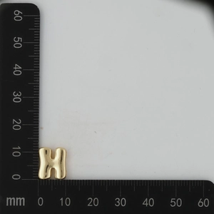 Close-up of golden letter H pendant measuring 11mm in height with polished finish
