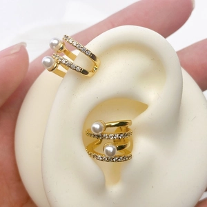 Close-up of golden ear cuff set with pearls and zircon stones on a silicone ear model