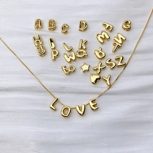 Gouden alfabet ketting set met LOVE hangers in ballonstijl op zijden achtergrond