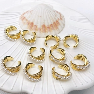 Macro view of multi-layer C-shape gold-plated ear cuffs with white pearls and zircons