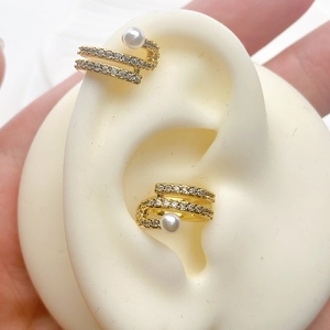 Detail view of gold snake-shaped ear cuff with pave zircon and pearl on ear model
