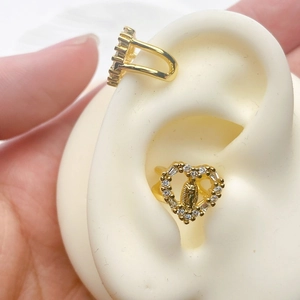 Detailed view of gold ear cuffs featuring sparkling zircons and a religious relief motif