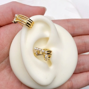 Detailed macro of gold plated ear cuffs with cubic zirconia and pearls on ear model