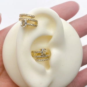 Detailed close-up of gold triple-layer ear cuff with tiny diamonds and oval stones
