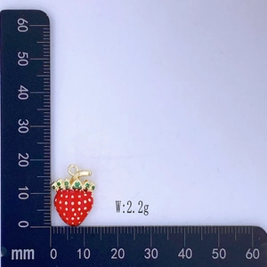 Dettaglio macro del ciondolo a fragola rossa con strass verdi che mostra scala 18mm