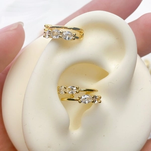 Detailed view of gold plated ear bone clips with oval zircons on a silicone ear model