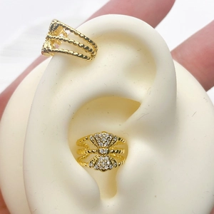 Detail view of gold-plated snake bone ear cuffs with sparkling zircons and twist texture