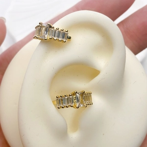 Detailed close-up of golden ear cuffs with rectangular zircon stones on ear model
