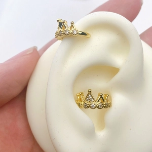 Detail of gold crown ear cuffs with white zircons shown on an ear model with no piercing