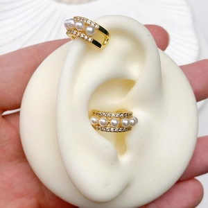 Detailed close-up of C-shaped 18K gold-plated ear cuff with white pearls and zircons