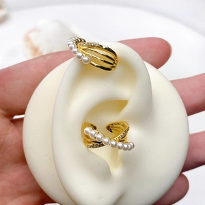 Macro detail of gold plated C-shaped ear cuffs with pearls and zircon on ear model