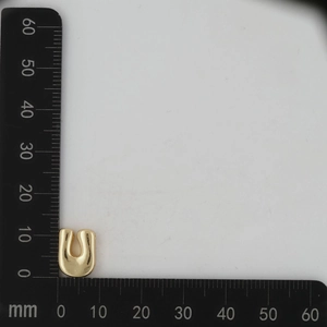Detail view of 18k gold letter U pendant showing 12mm dimensions on a scale ruler