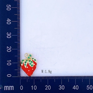 Dettaglio dell'orecchino a fragola rossa con peso di 1,9g su una scala graduata blu