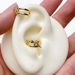 Macro view of gold snake ear cuffs featuring sparkling crystals and emerald green eyes